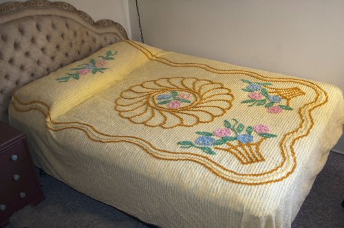 This is a picture of a full-size vintage yellow chenille bed with a design of flower baskets .